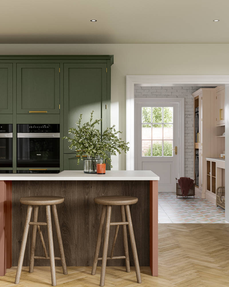 Tall Wardley kitchen cabinets  with built-in ovens, a kitchen island in shade Clay with wooden panelling by seating area and matching wooden bar stools.