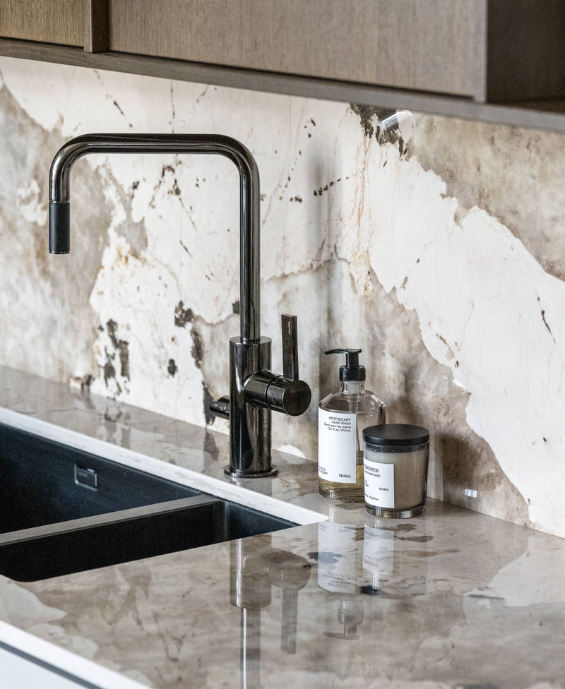 Sort vask og mørkt blandebatteri på kjøkkenet Line Korn og Favn finert eikedør i brunbeis fra Sigdal, med matchende benkeplate og splashback.