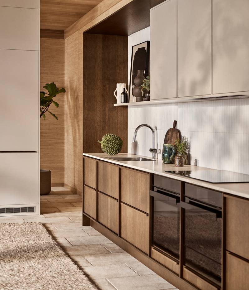 Mørk eg køkkenbænk Forever Oak fra INVITA kombineret med overskaber Athena Sand, hvide fliser, bordplade og massiv ek håndtag, ovn og dampovn fra Siemens