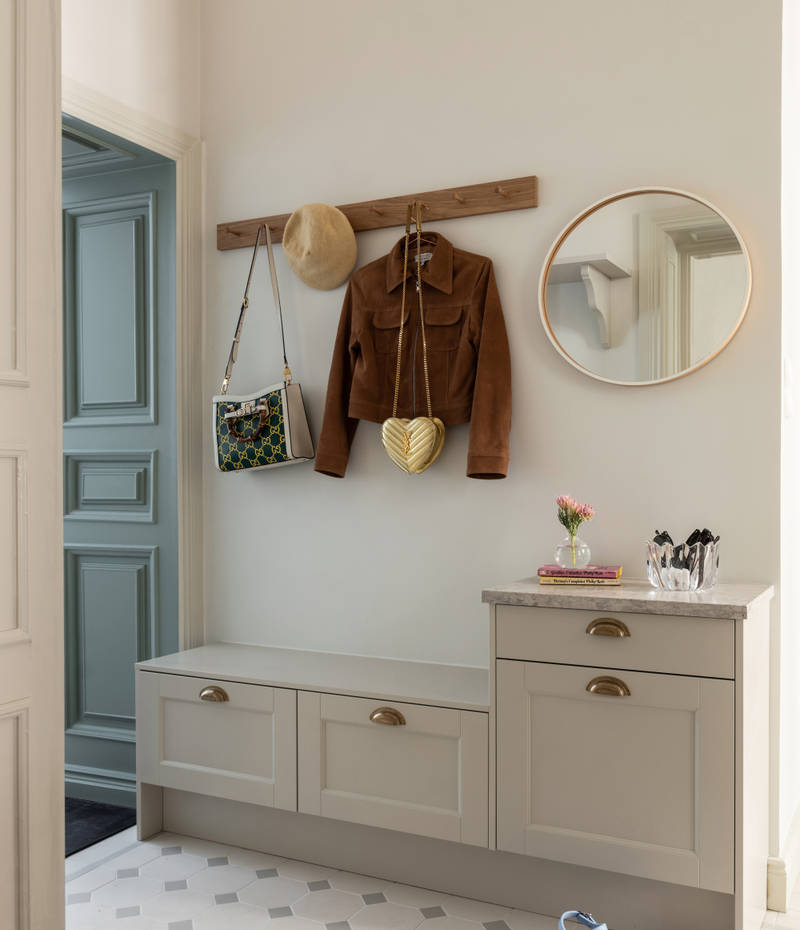 Hallskåp i Sandra Beijers lägenhet, lantliga luckan Fagerö i beige kulören Sand, låga skåp med knoppbräda och en spegel ovanför.