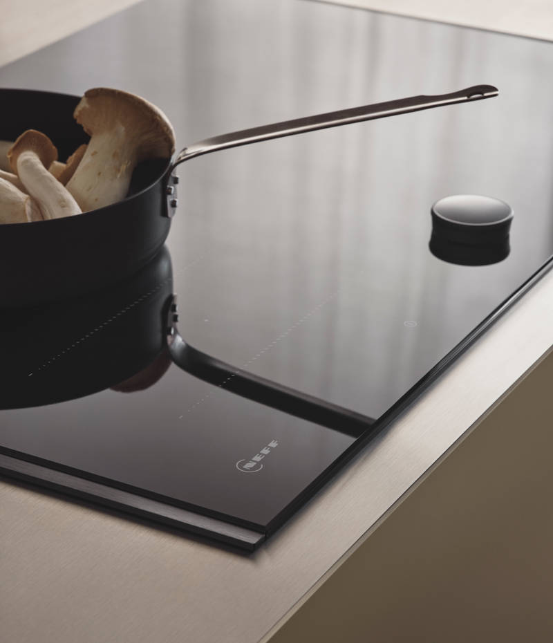 Nærbillede af induktionskomfur i Jubilæumskøkken fra INVITA med grønne skaber inspireret av 1970'erne og grønne fliser