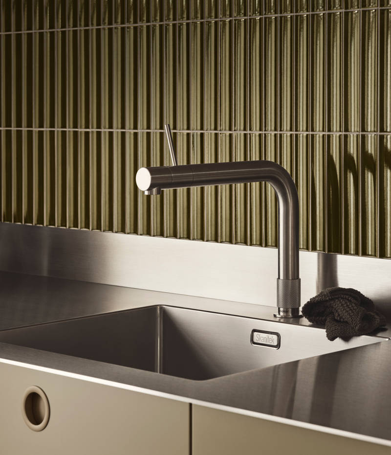 Nærbilllede av rustfrit stål vask og armatur i Jubilæumskøkken fra INVITA med grønne skaber inspireret av 1970'erne