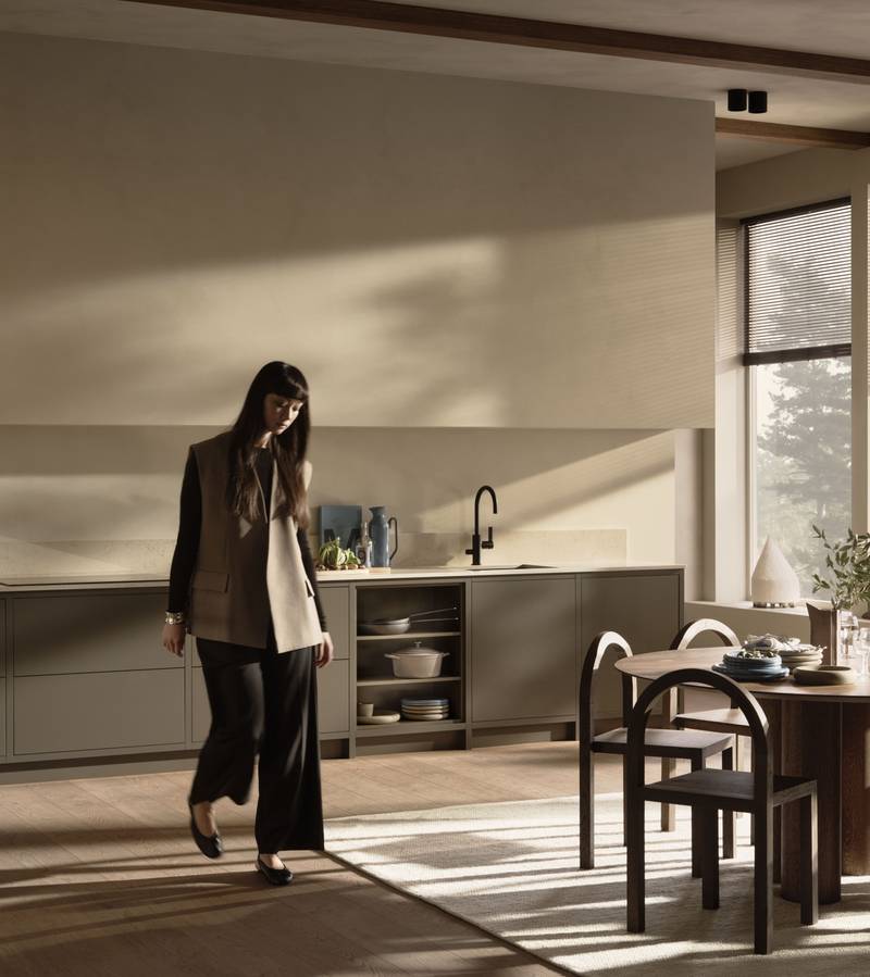 En kvinna går genom ett Warm Minimalism-kök från Marbodal.