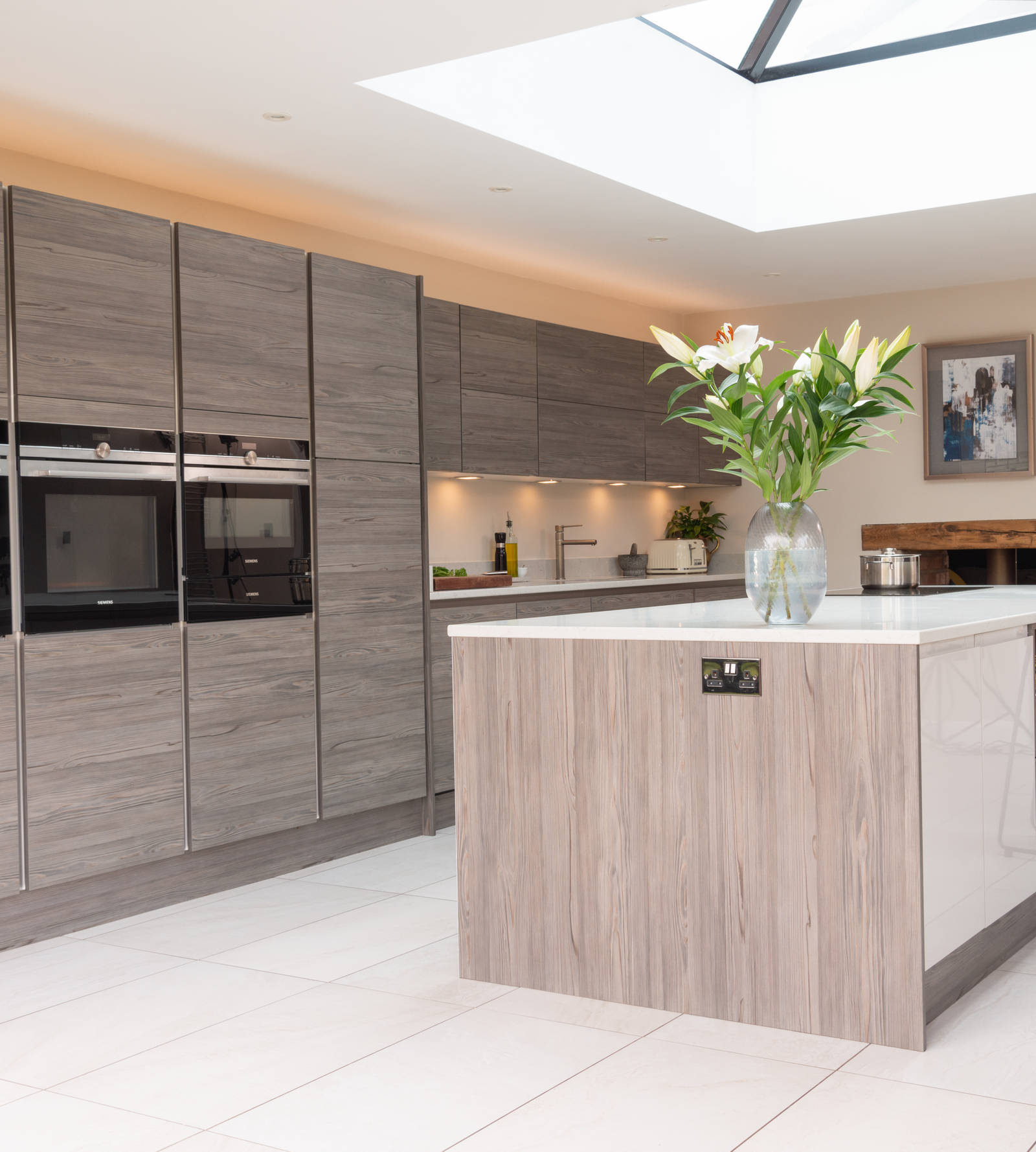 Angled view of Italian-inspired kitchen with an island decprated with a large vase of white lillies.
