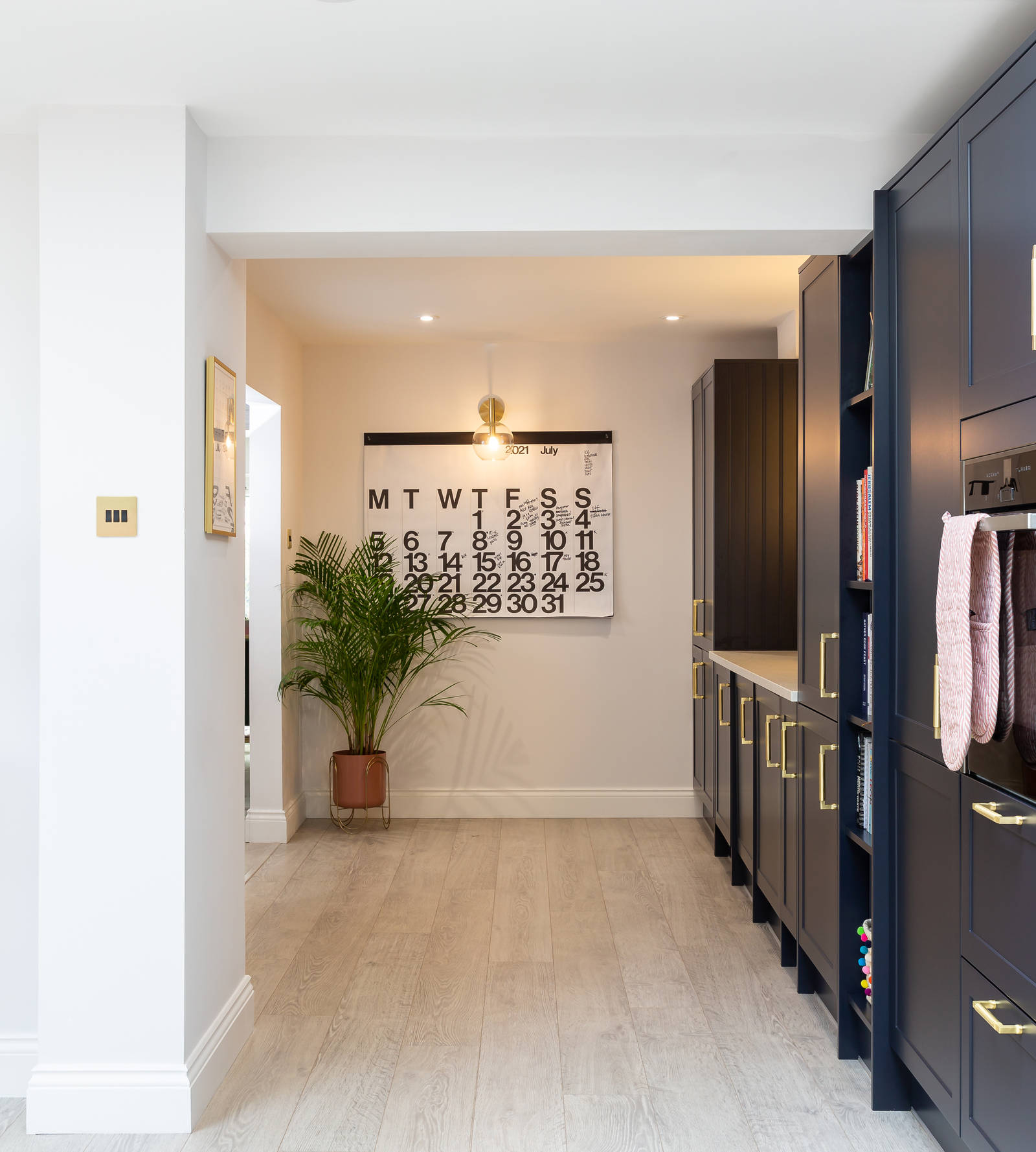 Dark blue shaker kitchen, large potted plats and black and white graphic decorations as well as a black metal frame glass door
