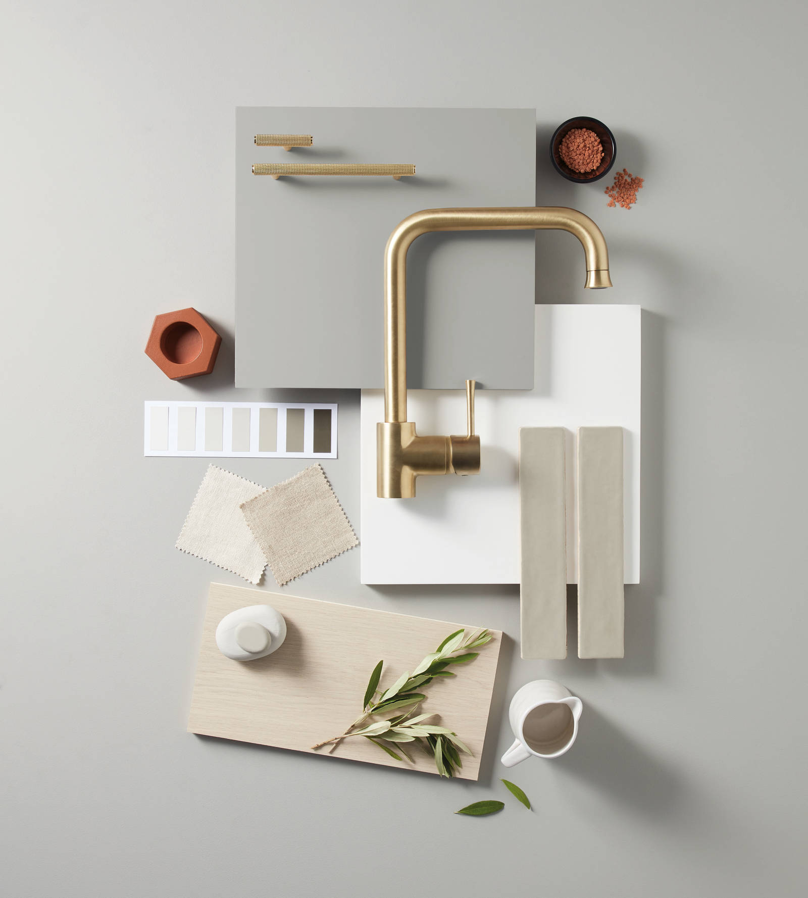 Colour samples of Hoxton Pebble, a brass tap, brass handles and light wood
