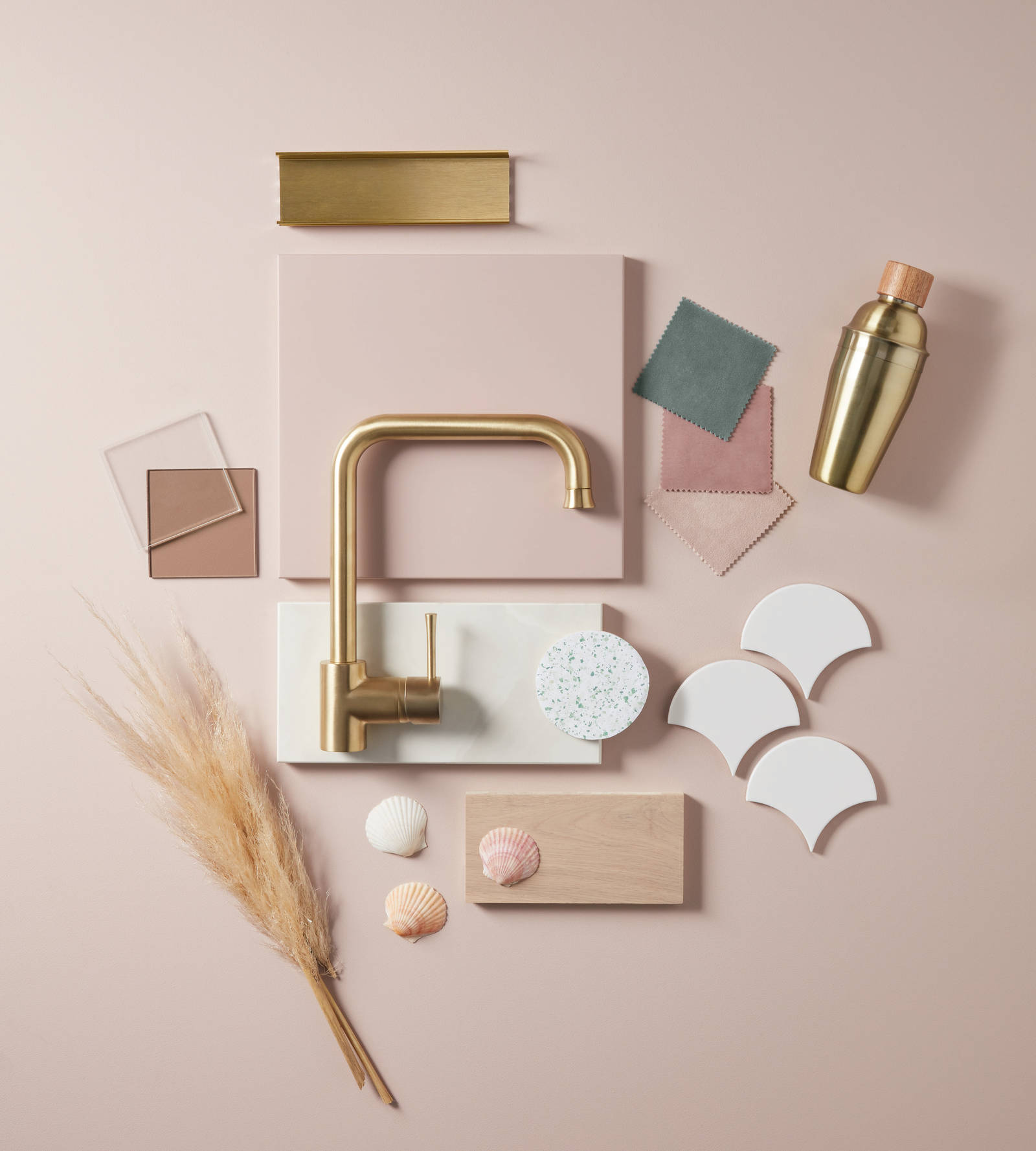 Moodboard of colour and material samples, a pink slab front with brass handles, a brass tap, a brass frink mixer, sea shells and a light wood sample.