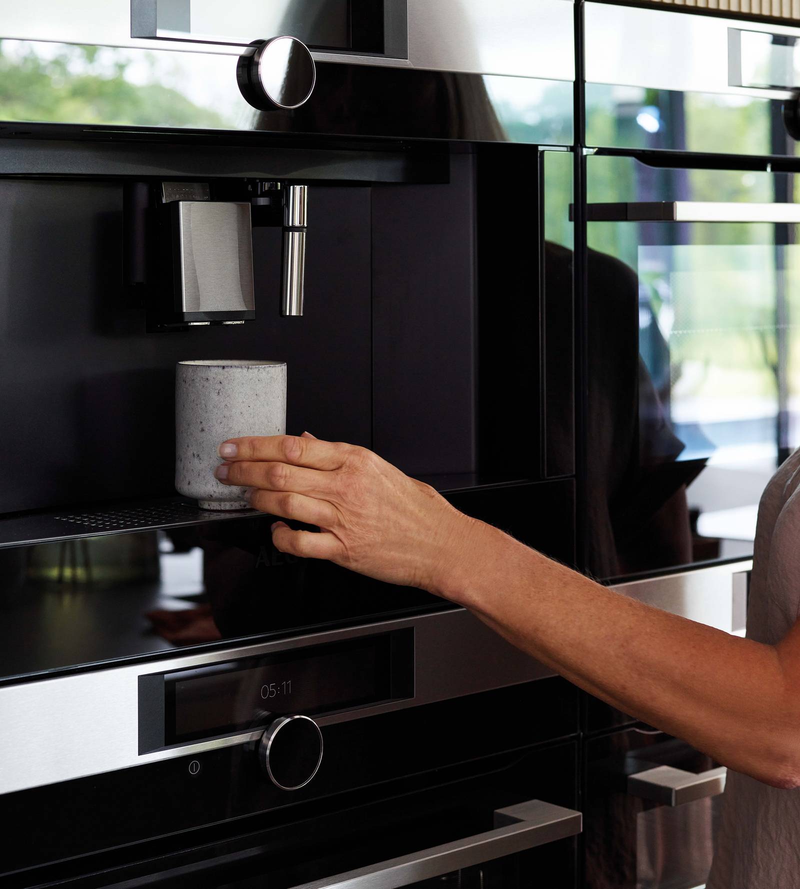 Woman using integrated coffee machine in Nordic Nature fluted oak kitchen