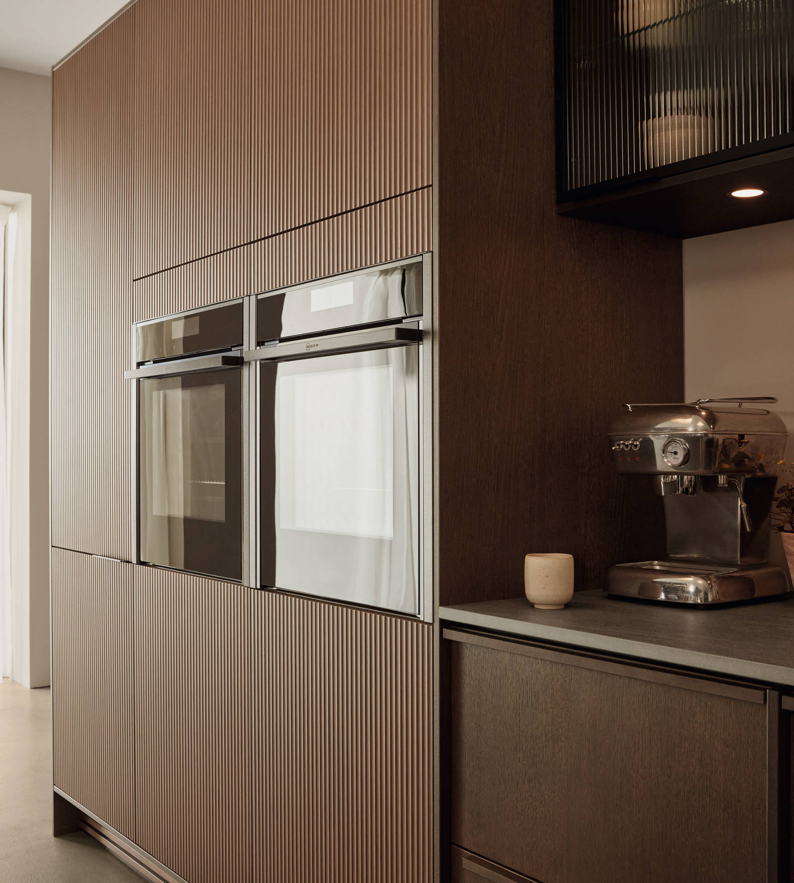 Brown kitchen cabinets with built-in ovens and a gray countertop. | HTH