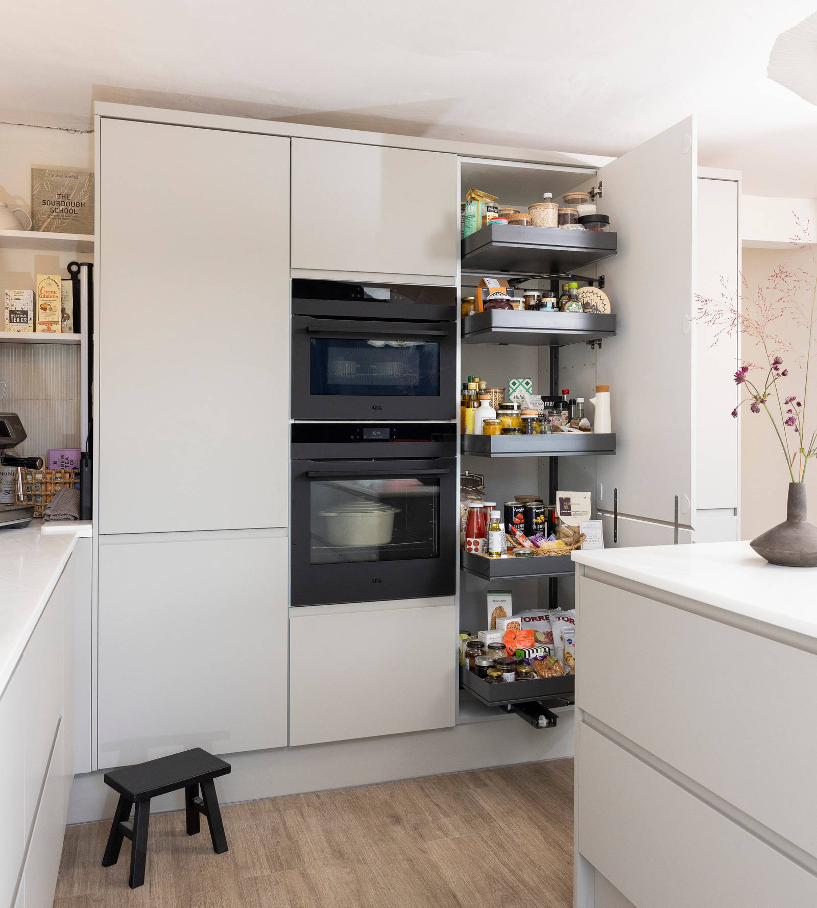 View of opened tall pull-out larder cupboard matt finish Luna kitchen cabinetry from Magnet in a neutral shade.
