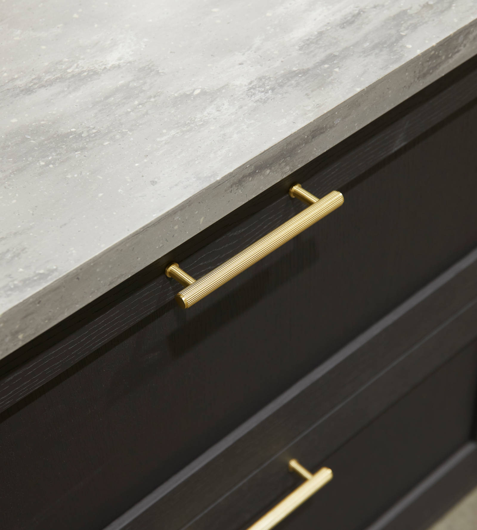 A close-up view of Ambleside drawer frontals in Graphite, with brass bar handles and grey worktop.