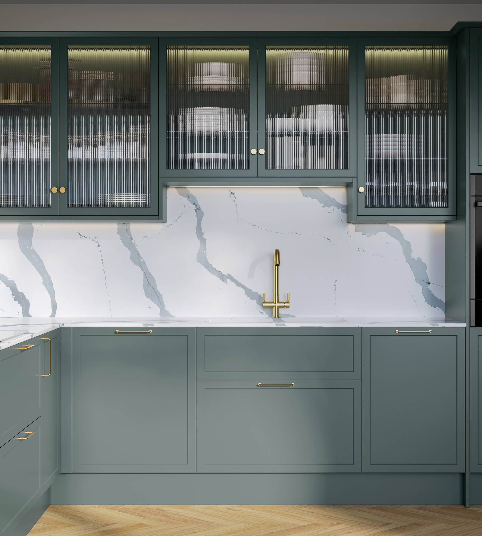 Modern Shaker kitchen Brunswick Spruce, a muted green shade, wall cabinets with fluted glass doors, Quartz Bianco Calacatta worktop and splashback, brass accessories like knobs, handles and tap, and a light wood herringbone floor.
