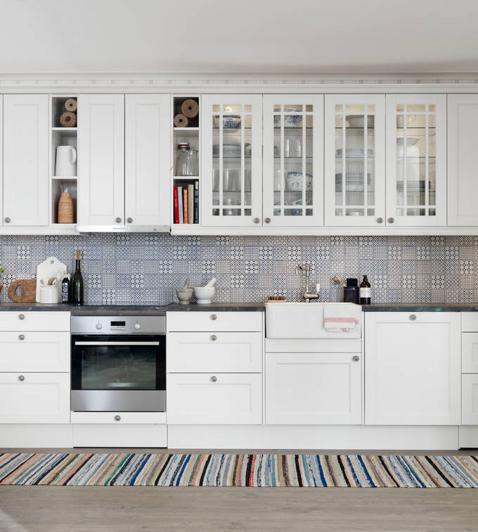 Marbodal Fagerö Frost - kök med vitrin, matchande kakel och lugna färger med en känsla av skärgård och med en flirt åt tidigt 1900-tal. Bänkskivan med stenkaraktär och en tidstypisk blandare i nedfälld porslinsho förstärker intrycket.