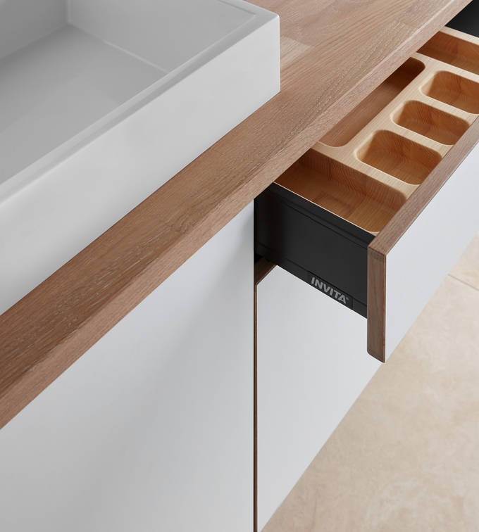 Nærbillede av åpen badeværelsesskuffe i badeværelse Comet Frost fra INVITA, med bordplade tre og hvid vask
