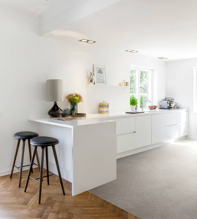 Grebsfrie hvide køkkenet Highline Frost med indfræsede greb i lågerne fra INVITA, hvid bordplade og barstole på halv køkkenø