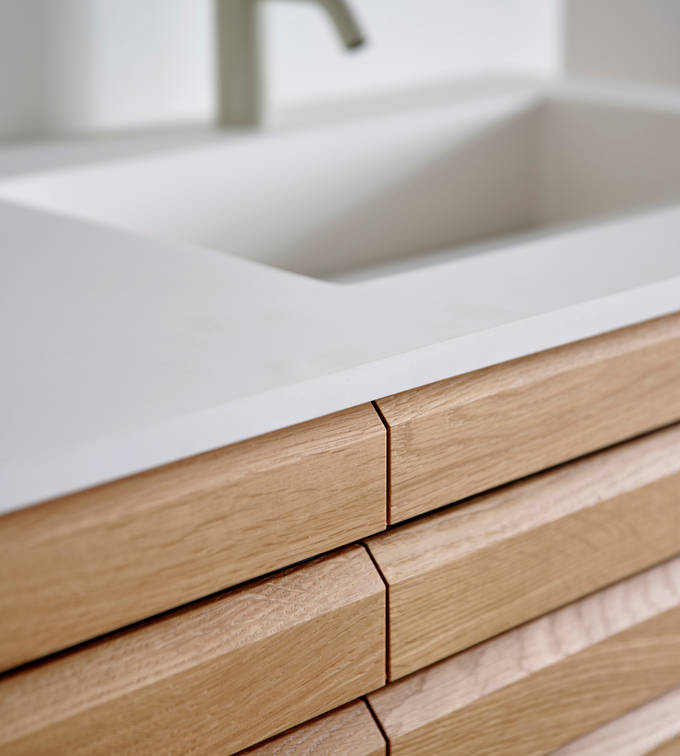 Nærbillede af snedkerbadeværelse Ikon Finér eg natur fra INVITA med håndplukkede, massive egetræslameller med hvid vask