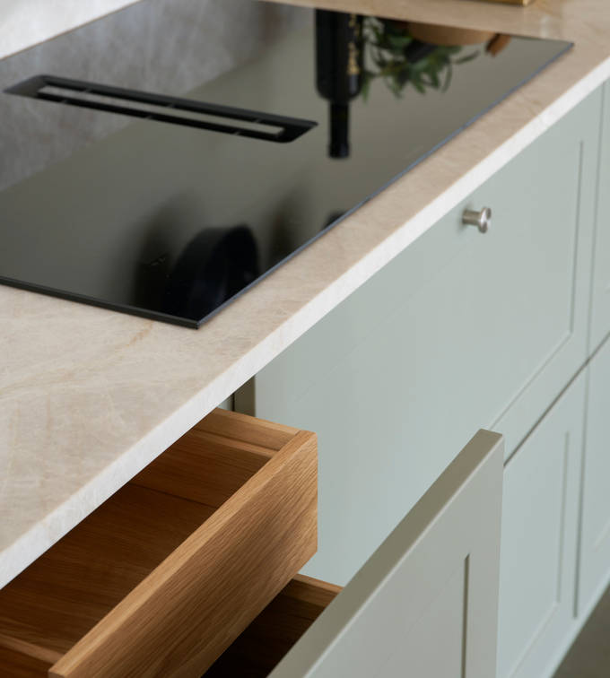 Nærbillede af induktionskomfur Grønn retrokøkken Square Salvie køkken fra INVITA med rustfri stål håndtag, armatur og vask med grå marmor bordplade