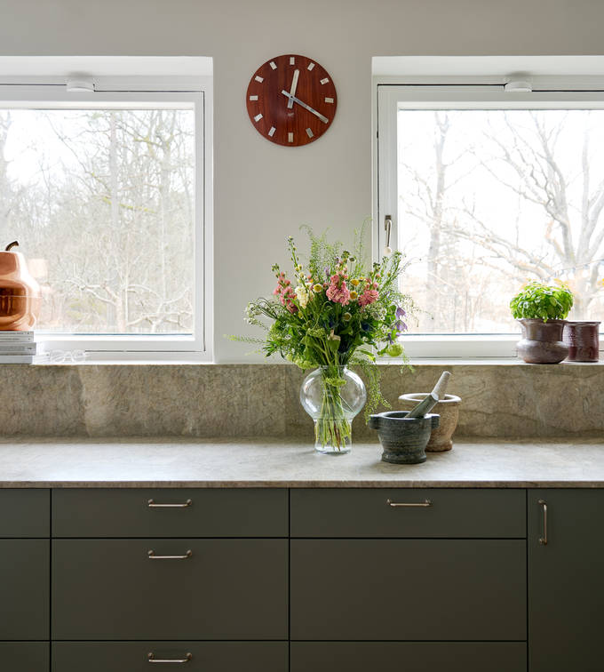 Inredningsprofilen Svante Öquists kök från Marbodal, Arkitekt Plus i den gröna kulören Tall med bänkskiva och matchande stänkskydd i kvartsit. Två stora mortar i marmor vilar på bänkskivan.