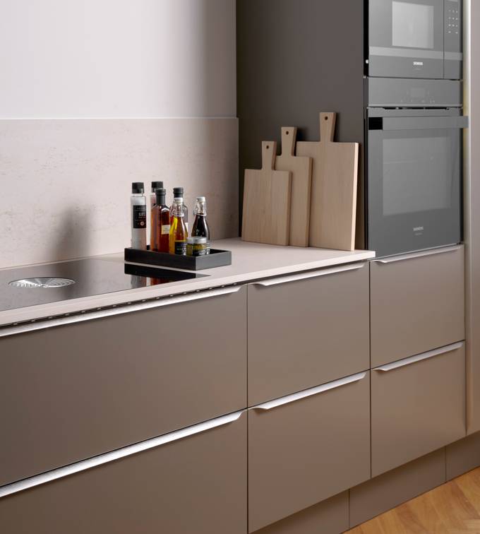 Minimalistisk brun køkken Newline Bark fra INVITA med indbygningsovne i højskabe, diskret greb i stål og lys beige bordplade med matchende splashback