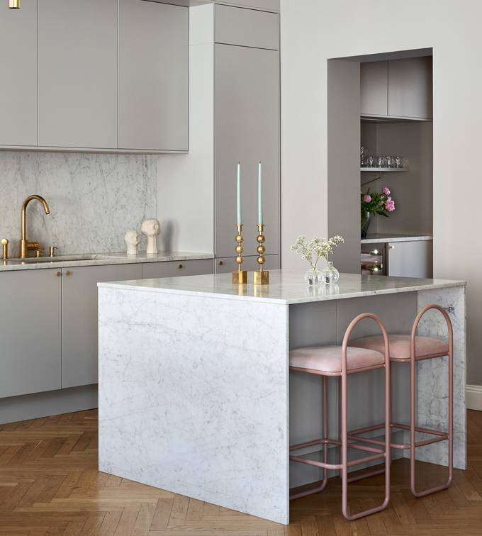 Lys grå Athena Sky køkken fra INVITA, køkkenø med dekorativ side og bordplade i lys grå marmor, håndtag, vandhane og lysestager i messing