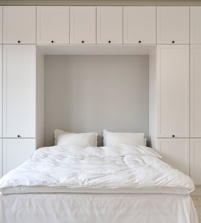 Hvid tidløs garderobe Square Sand fra INVITA omkring en seng med en kommode over, sorte greb på karmdøren