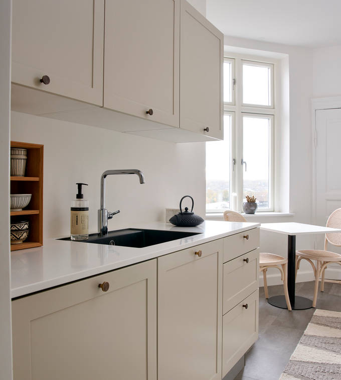 Beige retrokøkken Square Sand køkken fra INVITA med messing håndtag, hvid bordplade