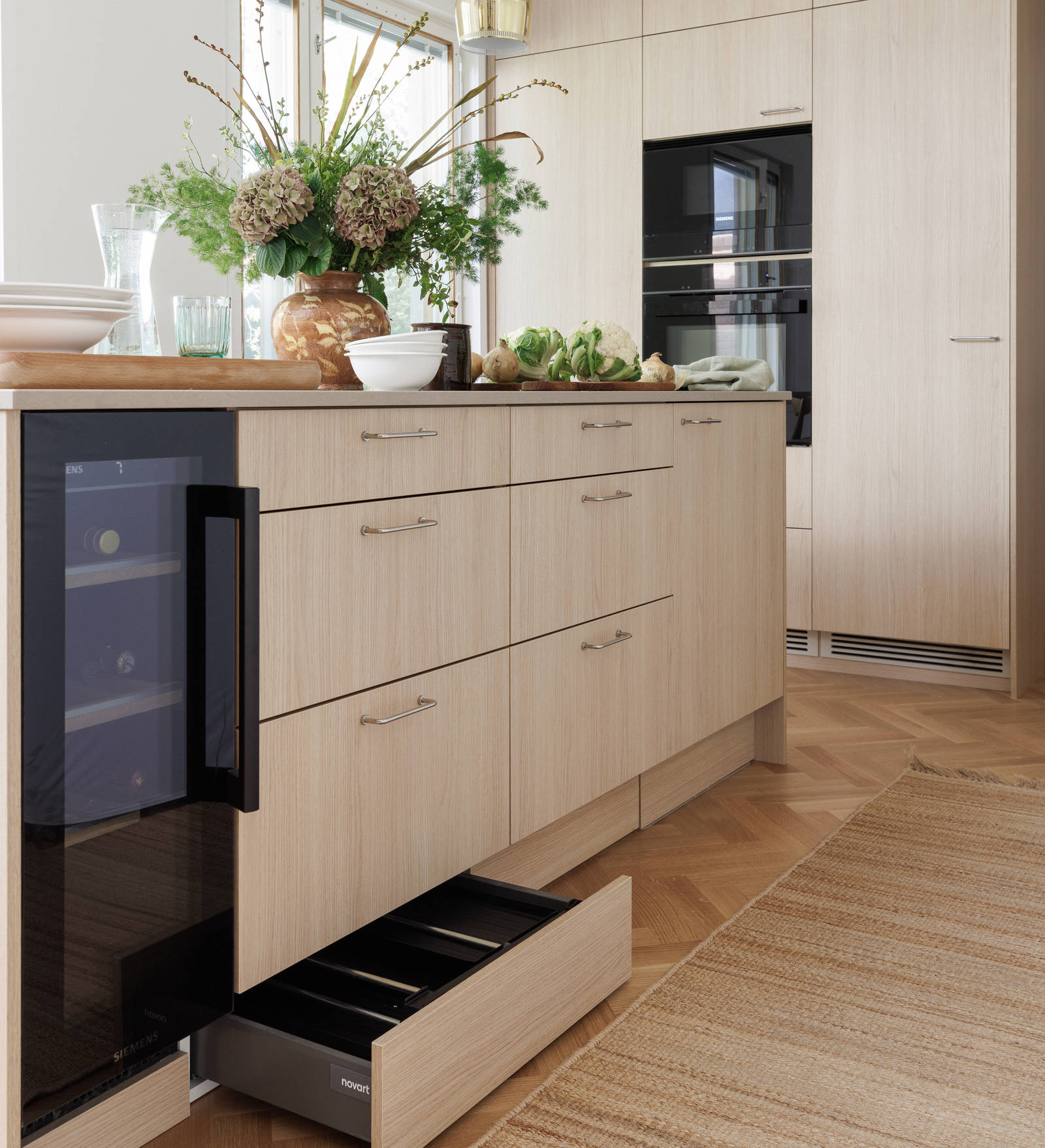 Aitoa luonnontammea Novartilta, yhdistelmä yhteensopivia puisia ja painonappikahvoja, keittiösaareke hanalla, tiskiallas ja ruostumattomasta teräksestä valmistettu työtaso.