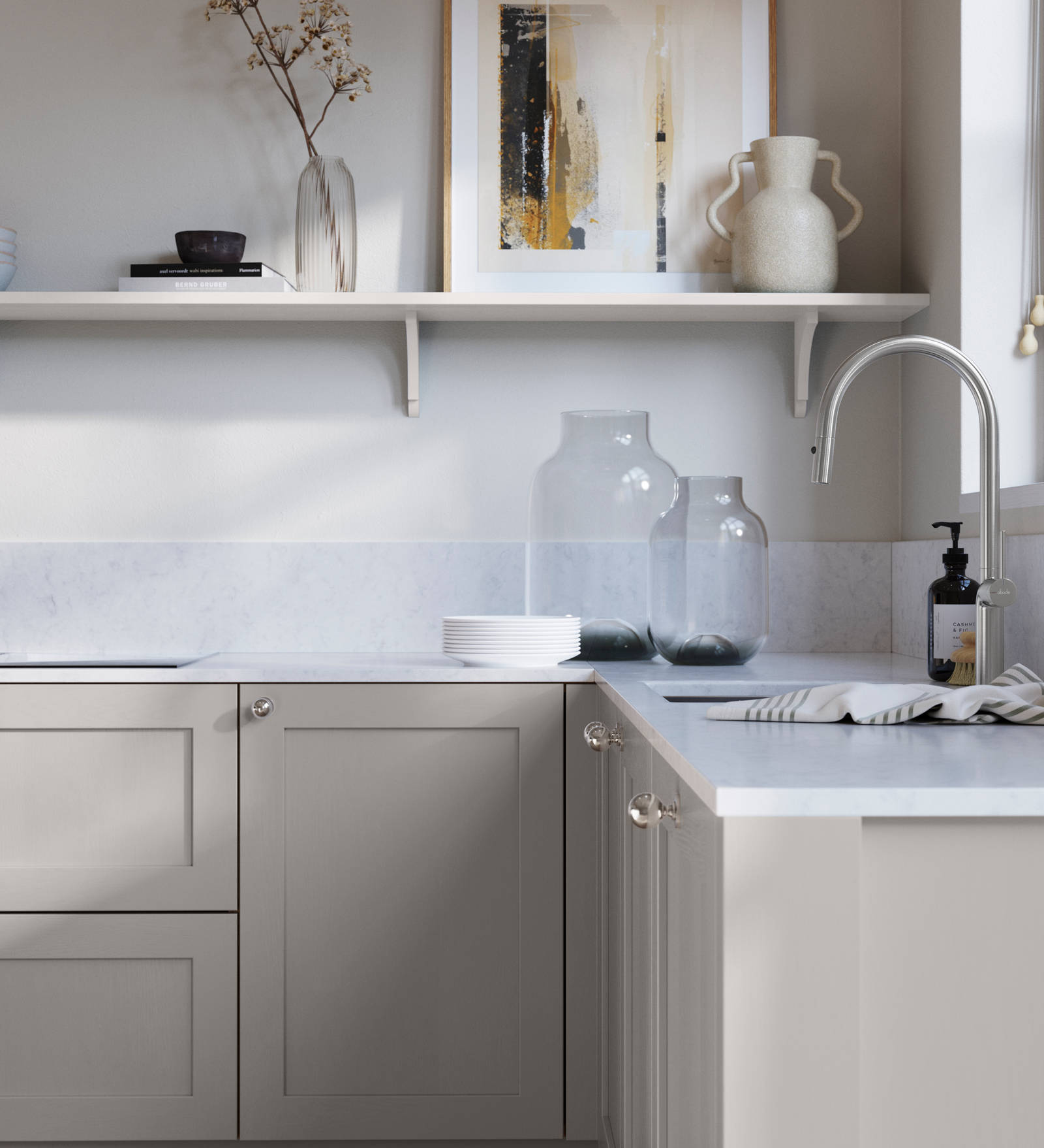Wardley Dove Grey kitchen cabinetry with steel knobs, steel tap, white marbled worktop and matching backsplash. An open shelf on the wall above cabinets with ceramics and a vase of flowers.
