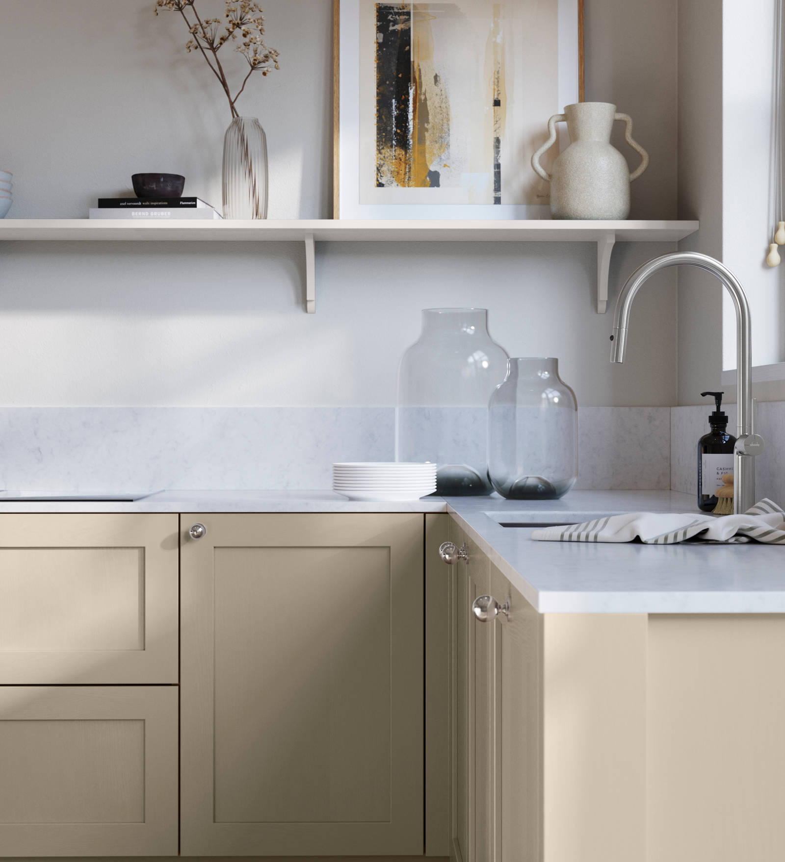 Wardley Pebble path kitchen cabinetry with steel knobs, steel tap, white marbled worktop and matching backsplash. An open shelf on the wall above cabinets with ceramics and a vase of flowers.