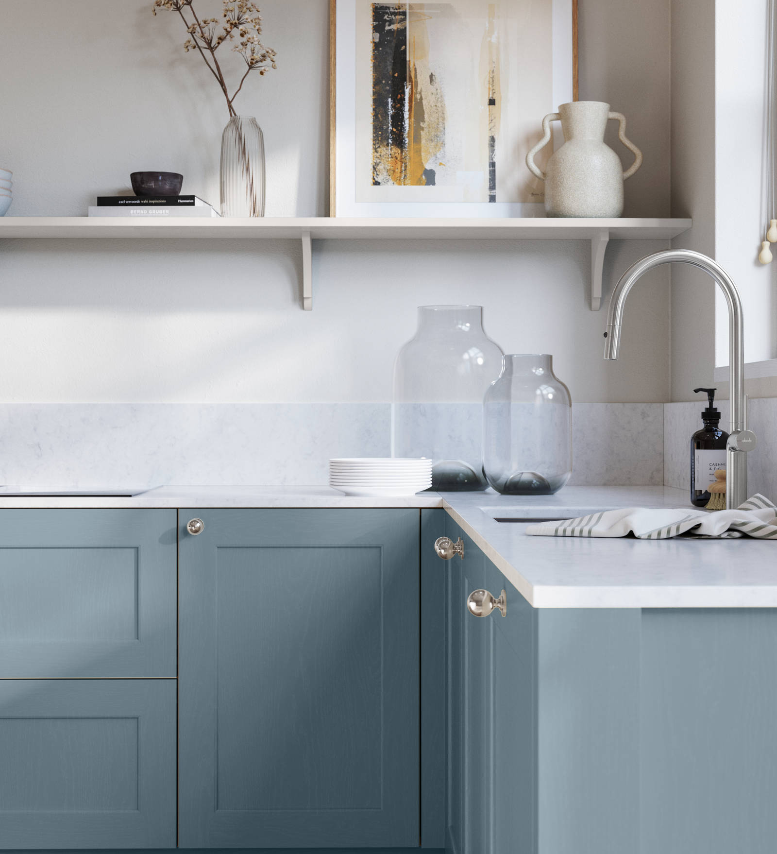 Ludlow, a traditional Shaker-style premium feel kitchen range with a visible woodgrain on its panelled doors here shown in the shade Portland Blue styled with steel knobs, steel tap, a white marbled worktop with matching splashback.