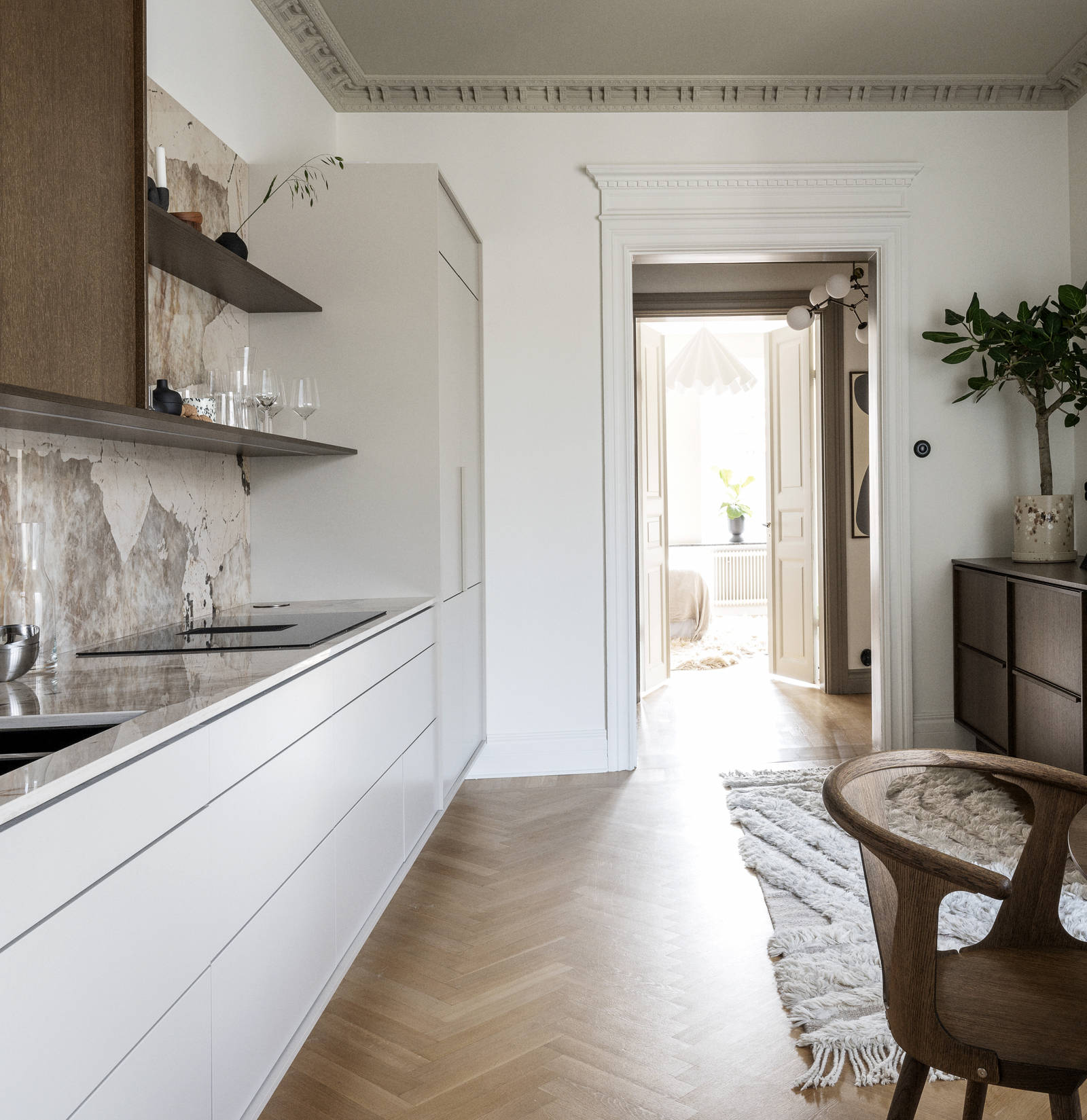 Køkken med en kombination af køkkenbord i beige Arkitekt Plus Sand med overskabe i Signatur Ekbacken fineret egetræslåge i brunbejdset fra Marbodal, bordplade og stænk, der matcher, og åbne væghylder i brunbejdset eg finer.