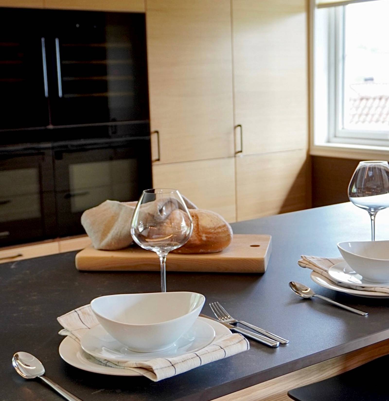 Modern eikekjøkken Amfi Natur fra Sigdal med sort marmor Dekton benkeplate og sorte håndtag.