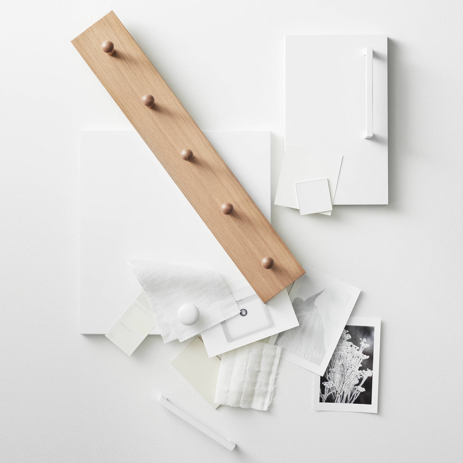 Moodboard med vit kökslucka, knoppbräda i ek, vita handtag, vita färgprover, svart-vita foton