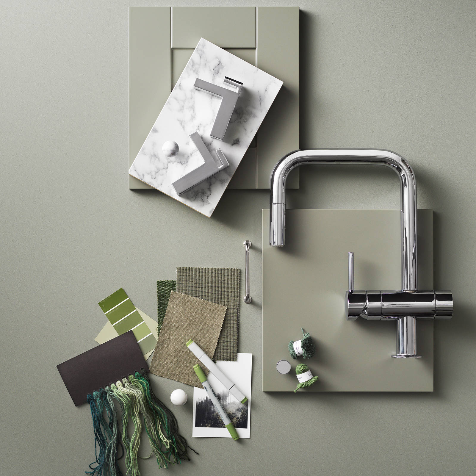 Moodboard med slät grön kökslucka, grön shakerlucka, blandare från tapwell i rostfritt stål, naturfärgade textilprover, handtag i rostfritt stål, marmor.