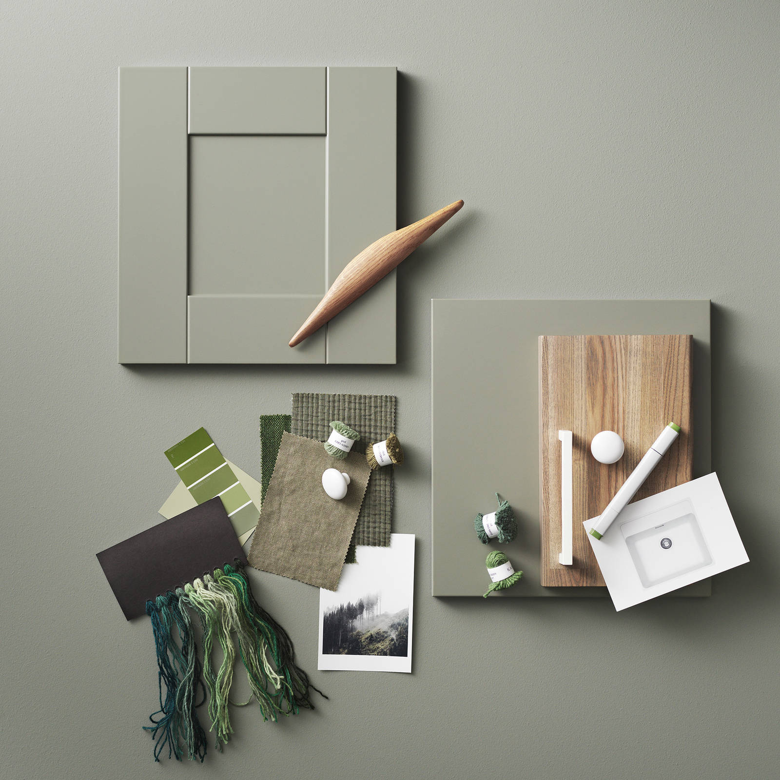 Moodboard med kökslucka i grön shakerstil, vita handtag och knoppar, träprover, färgprover och textiler i gröna toner