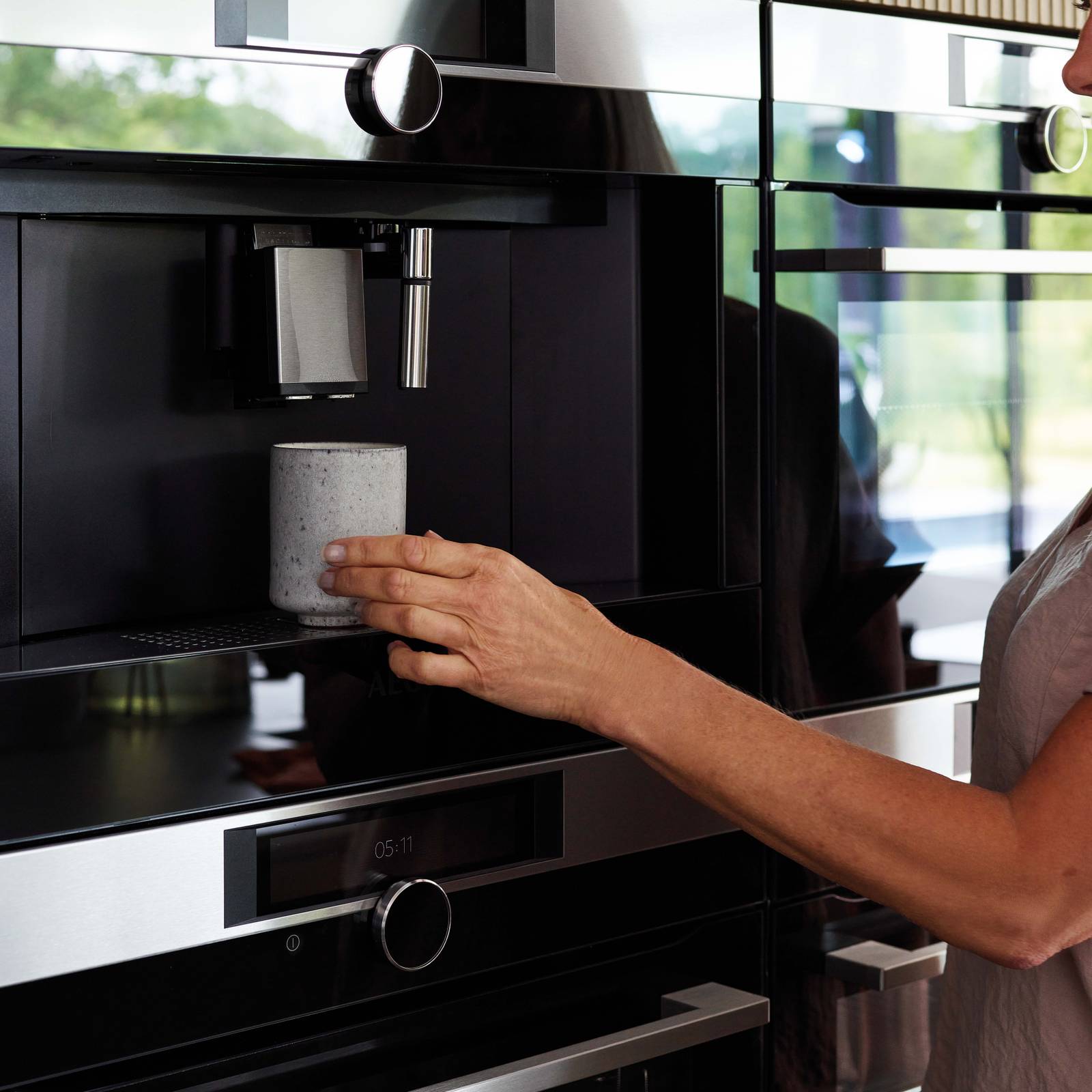 Woman using the integrated coffee machine in a Nordic Nature kitchen from Magnet