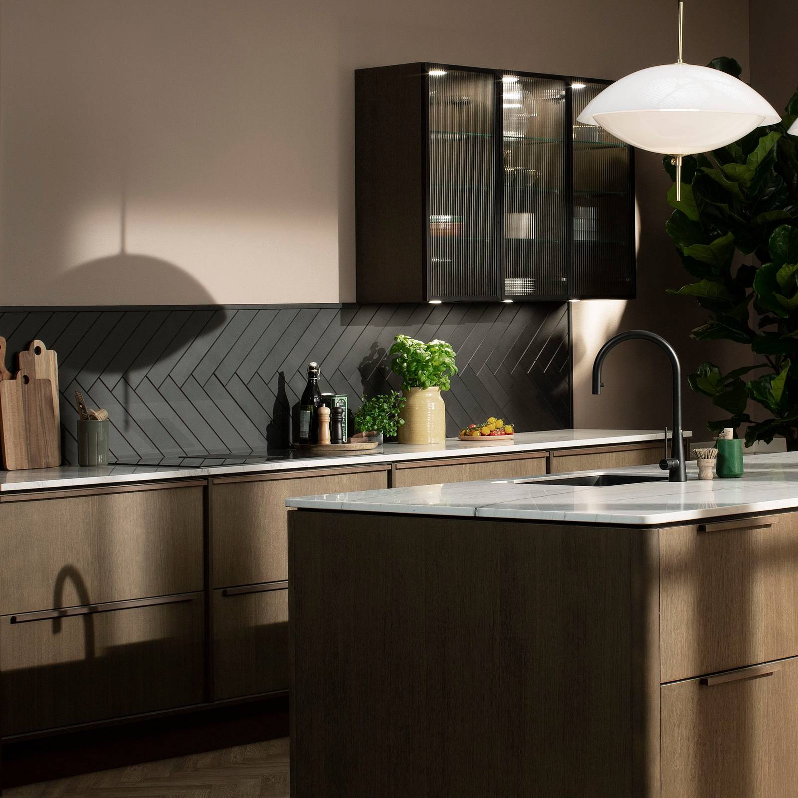 Mørk eg køkken Forever Oak fra INVITA med køkkenø og højskabe, med massiv tre mørk eg håndtag, vitrineskab med riflede glas og en tynd, sort aluminiumsramme