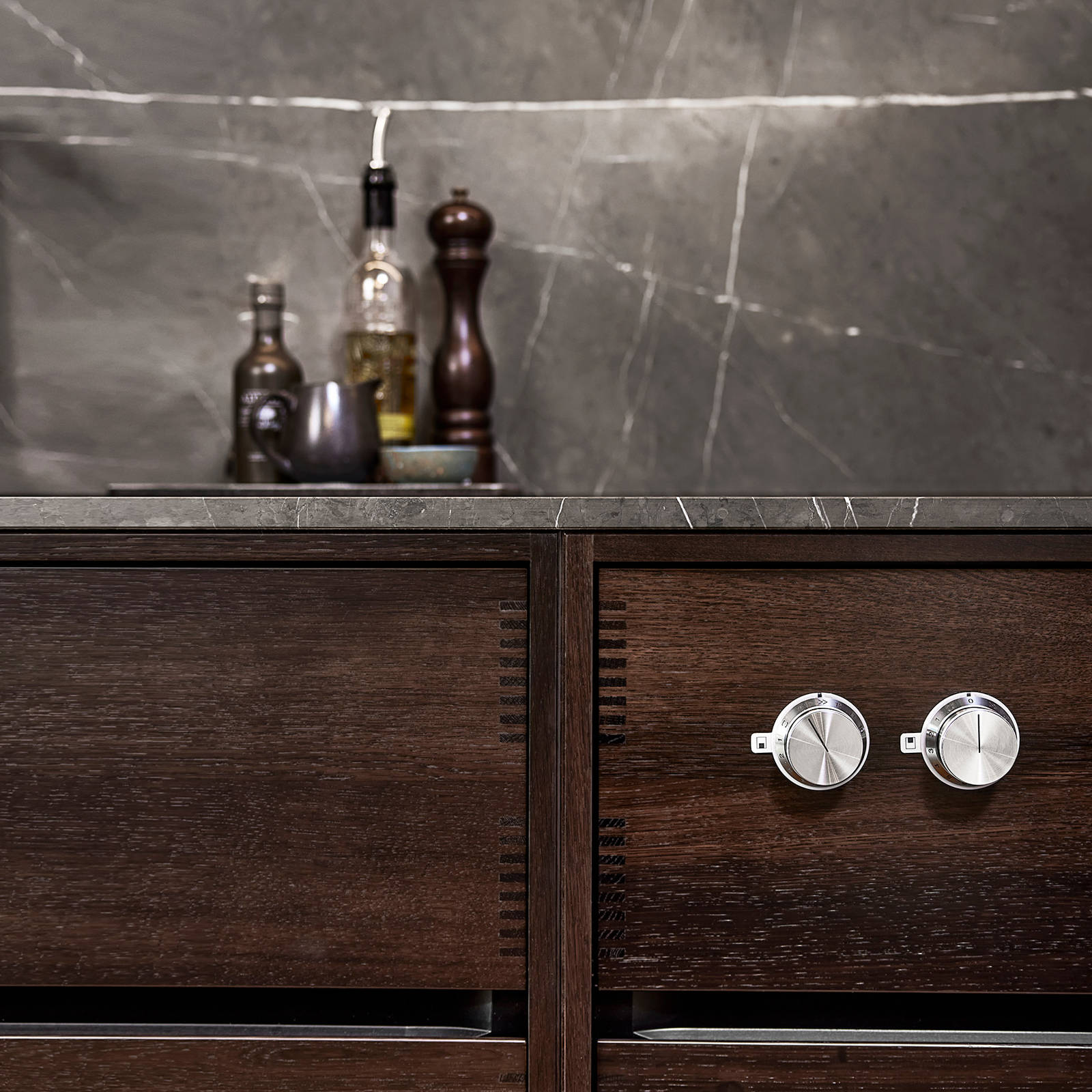 De massive, oplyste betjeningsgreb i rustfrit stål i Gaggenaus 400-serie er monteret på den lodrette overflade i køkkenet