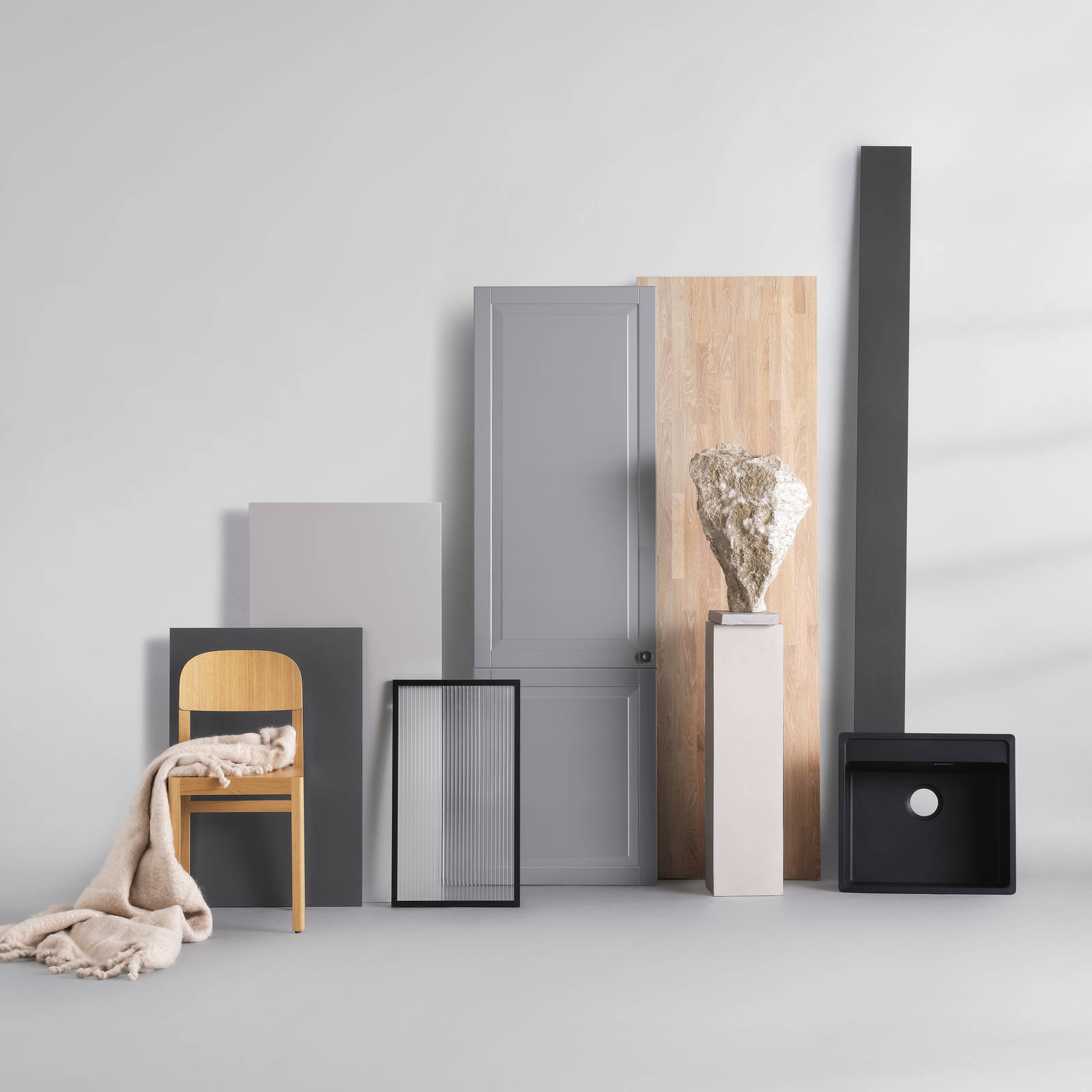 Grå køkkenskab i shaker-stil, glasskab med riflet glas og sort metalramme, bordplade i massivt træ, sort vask og træstol