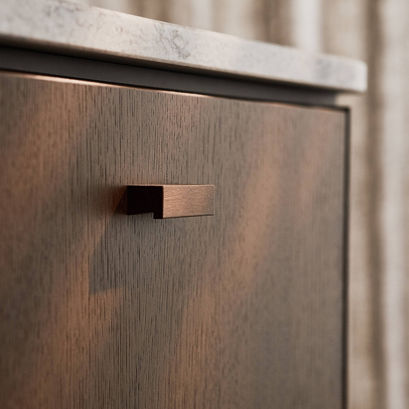 Nærbillede af køkkenø Forever Oak fra INVITA, mørk eg køkkenskabe og håndtag med Mont Blanc Quartzite bordplade