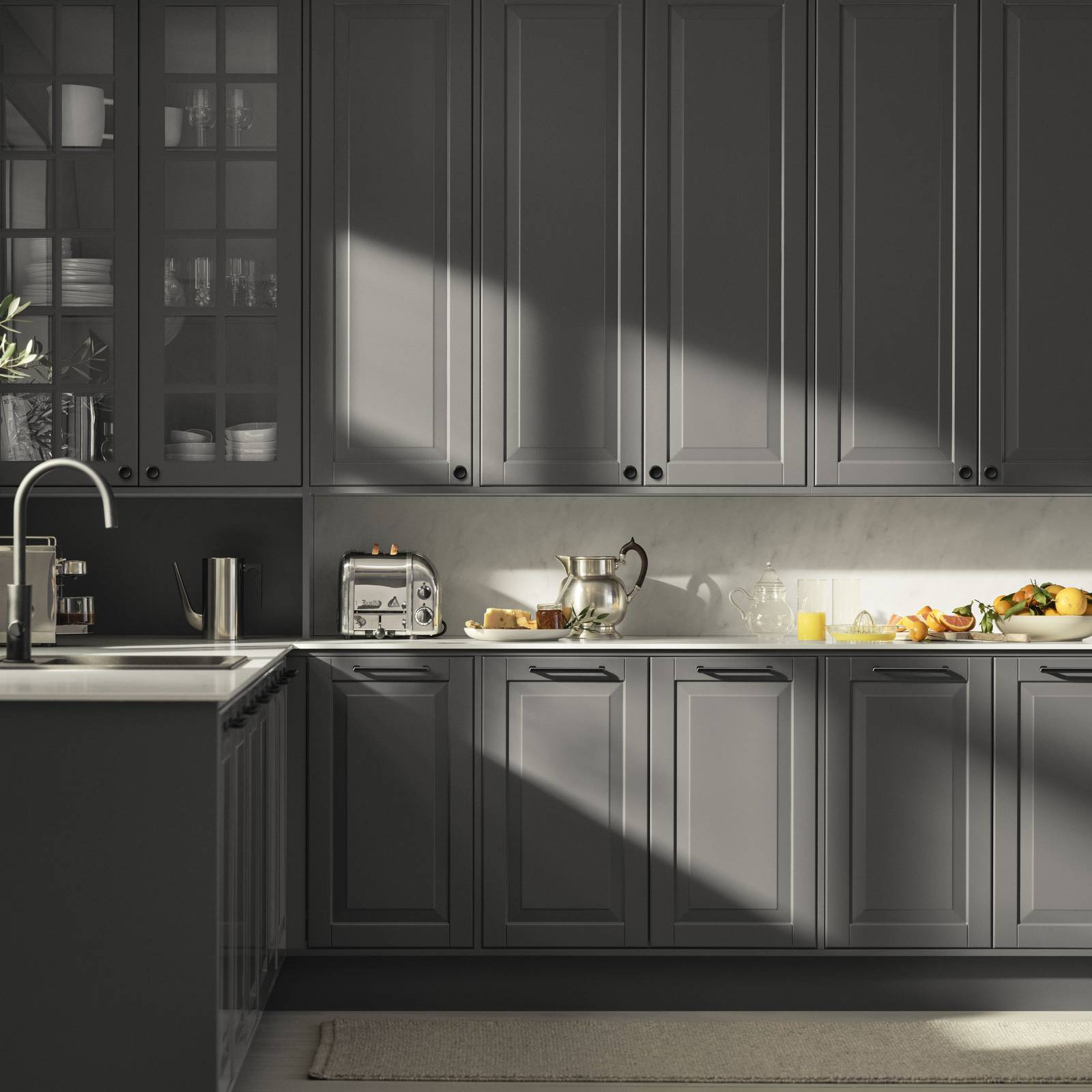 Mørk grå landkøkken Nordic Granit fra INVITA med fyldningslåger, sort håndtag, vitrineskab med sprosselåger og hvid marmor laminatbordplade
