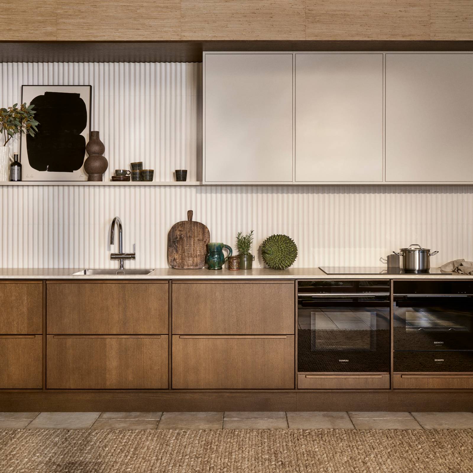 Mørk eg køkkenbænk Forever Oak fra INVITA kombineret med overskaber Athena Sand, hvide fliser, bordplade og massiv ek håndtag, ovn og dampovn fra Siemens