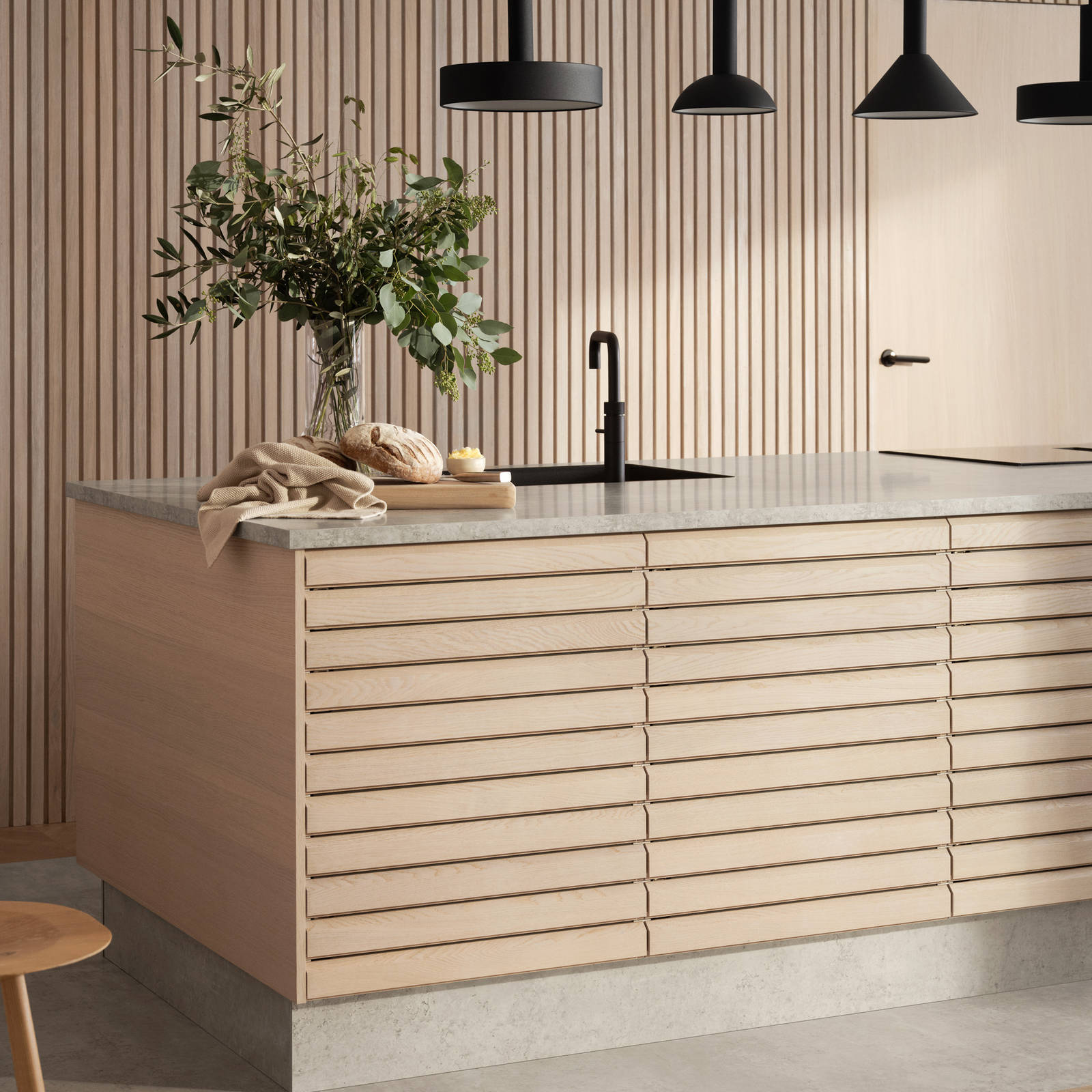 Nærbillede af egetræskøkkenø Ikon fra INVITA med håndsorterede lameller i massiv eg, mat sort armatur og sorte lamper