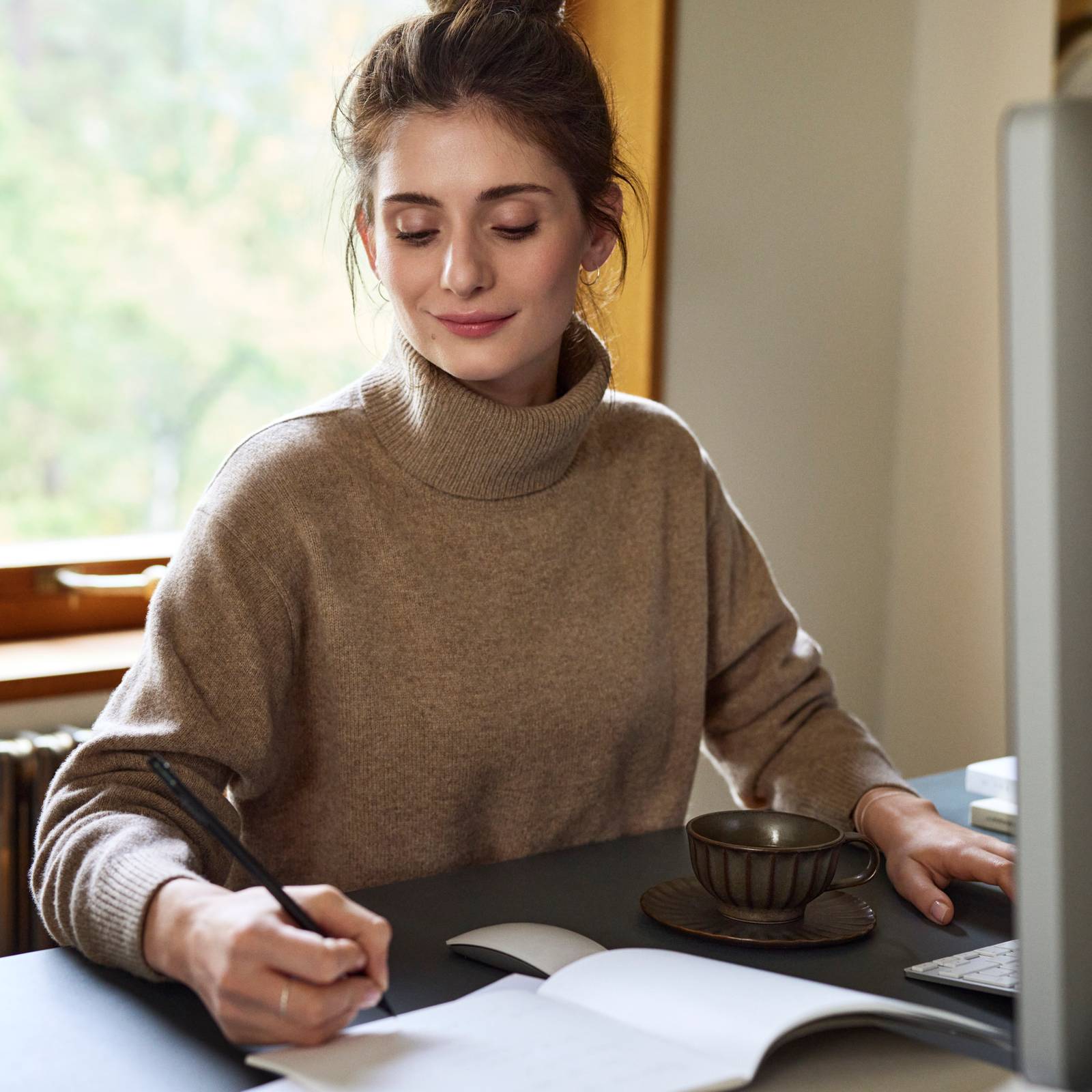 Kvinde gør anteckning framfør computeren