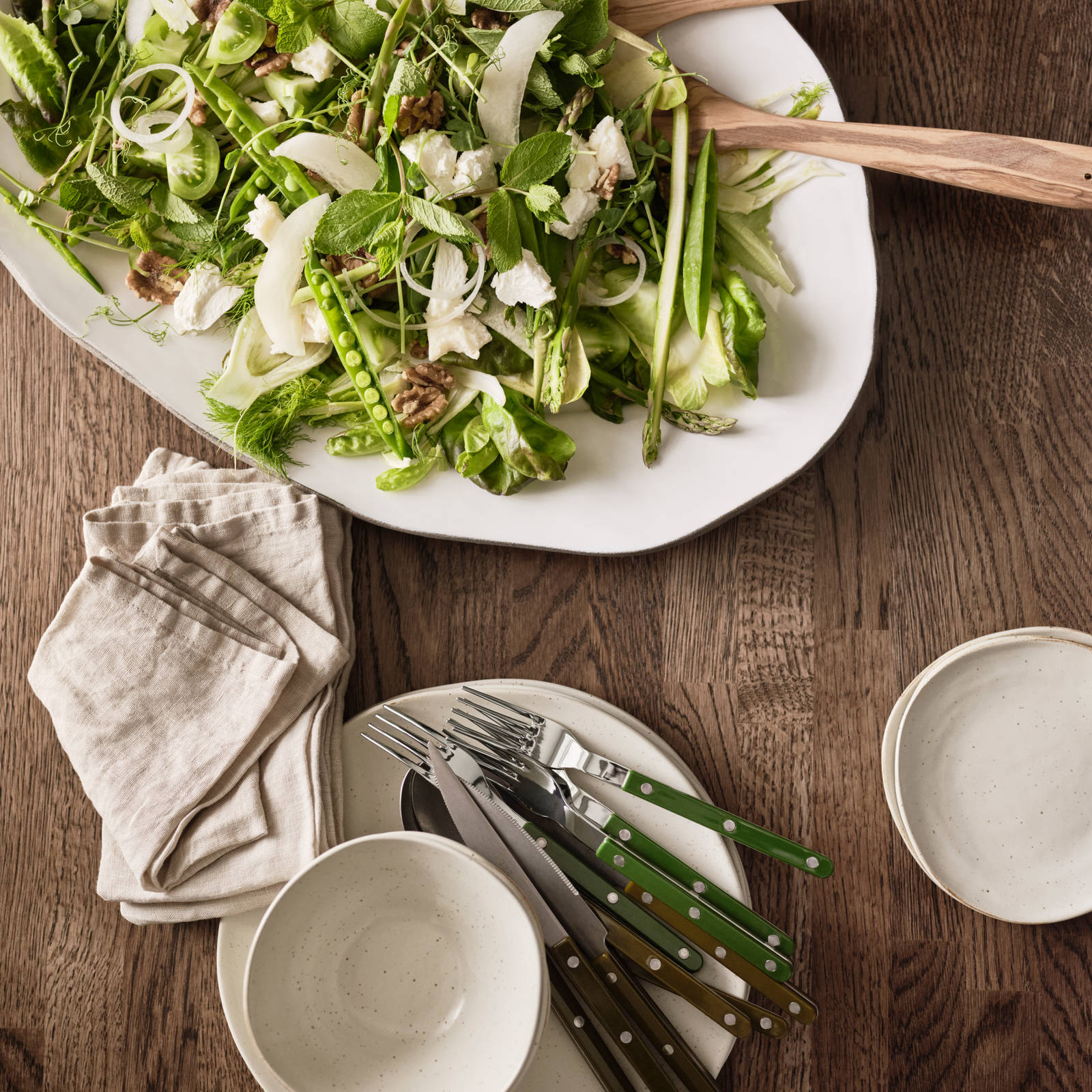 Bordplade i massivt træ ovenfra med porcelæn og en salat lagt ud