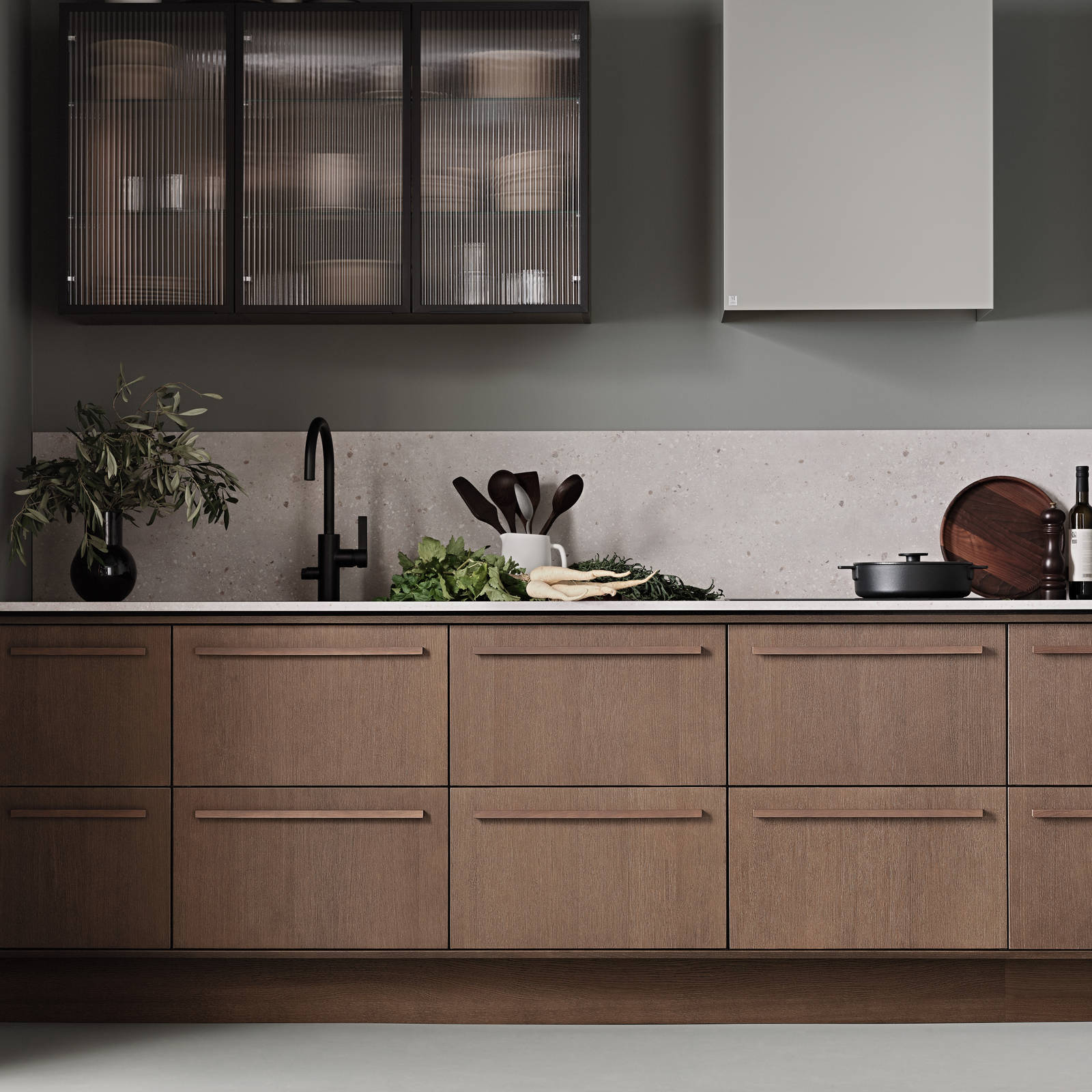 Køkken Forever Oak fra INVITA, mørk eg køkkenskabe med massiv tre mørk eg håndtag, komposit bordplade, sort armatur og vitrineskab med riflede glas i tynd, sort aluminiumsramme