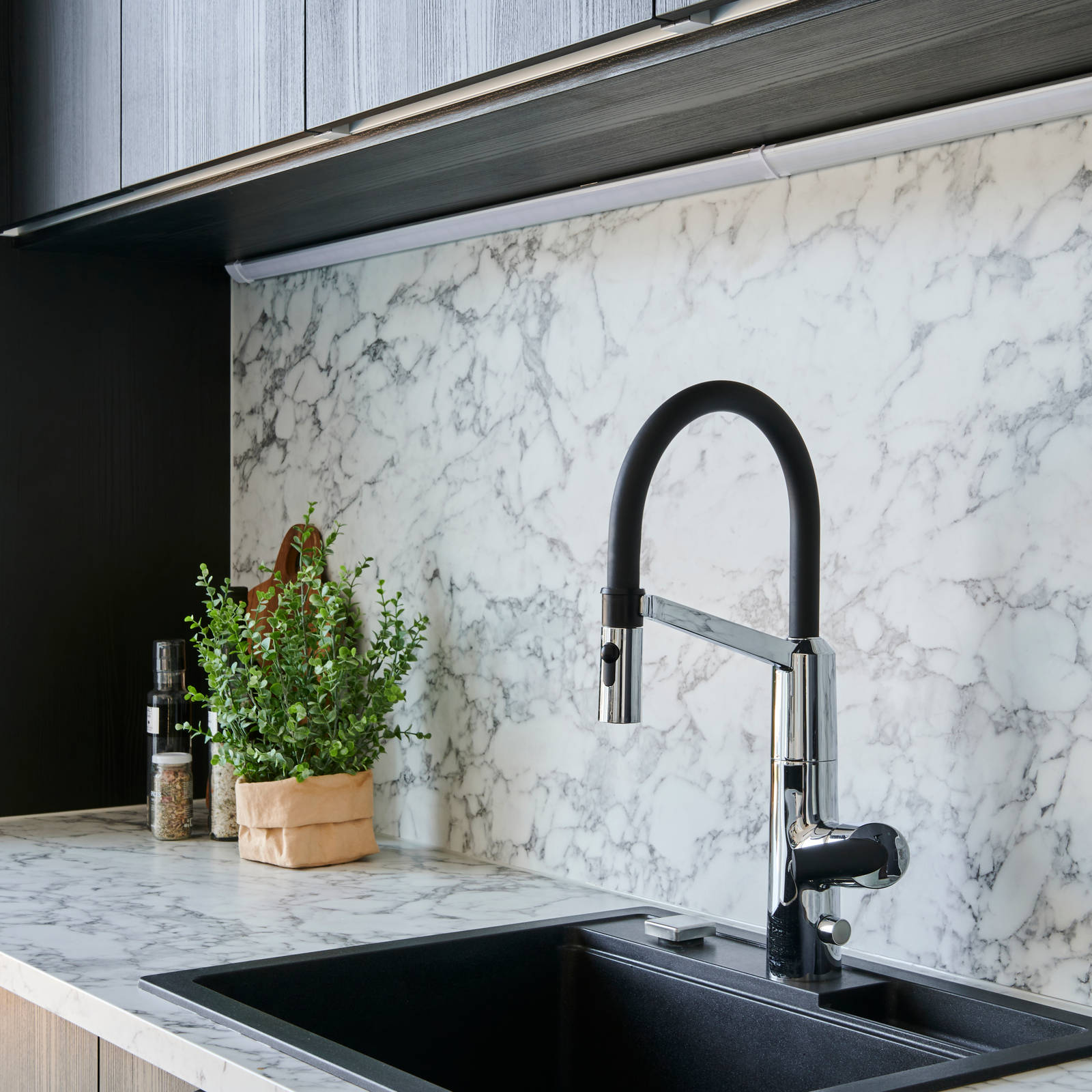 Tumma avokeittiö koostuu melamiiniovista tummassa sävyssä hiiltynyt puu. Myös vetimet ovat tummia olleessaan harjattu mattamusta lippavedin, minkä lisäksi tumma Stalan allas syventää värimaailmaa entisestään. Eloisa tasovalinta ja aamiaiskaapin vaalea sisus tuovat kokonaisuuteen mukavaa kontrastia.