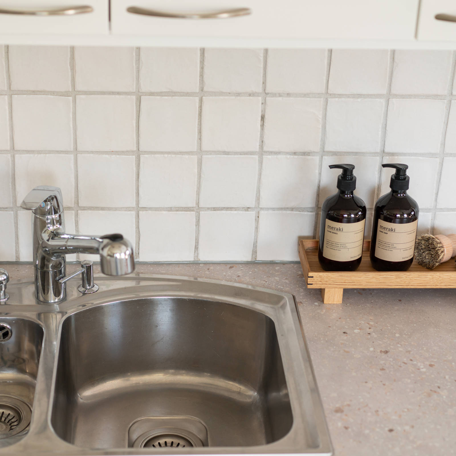 Oppvaskkum i rustfritt stål, hvit fliser sprutbak og beige benkeplate