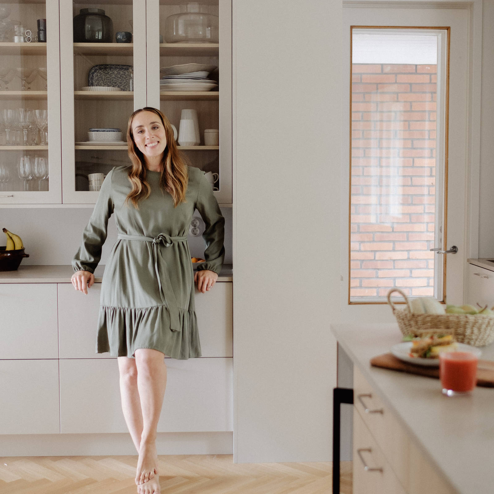 Anni Ihamäki toimivassa melamiini- ja laminaattikeittiössä Hiekassa ja lämminsävyinen vaalea tammimelamiini Novartilta, vitriinikaapeilla ja Quartz-tasolla