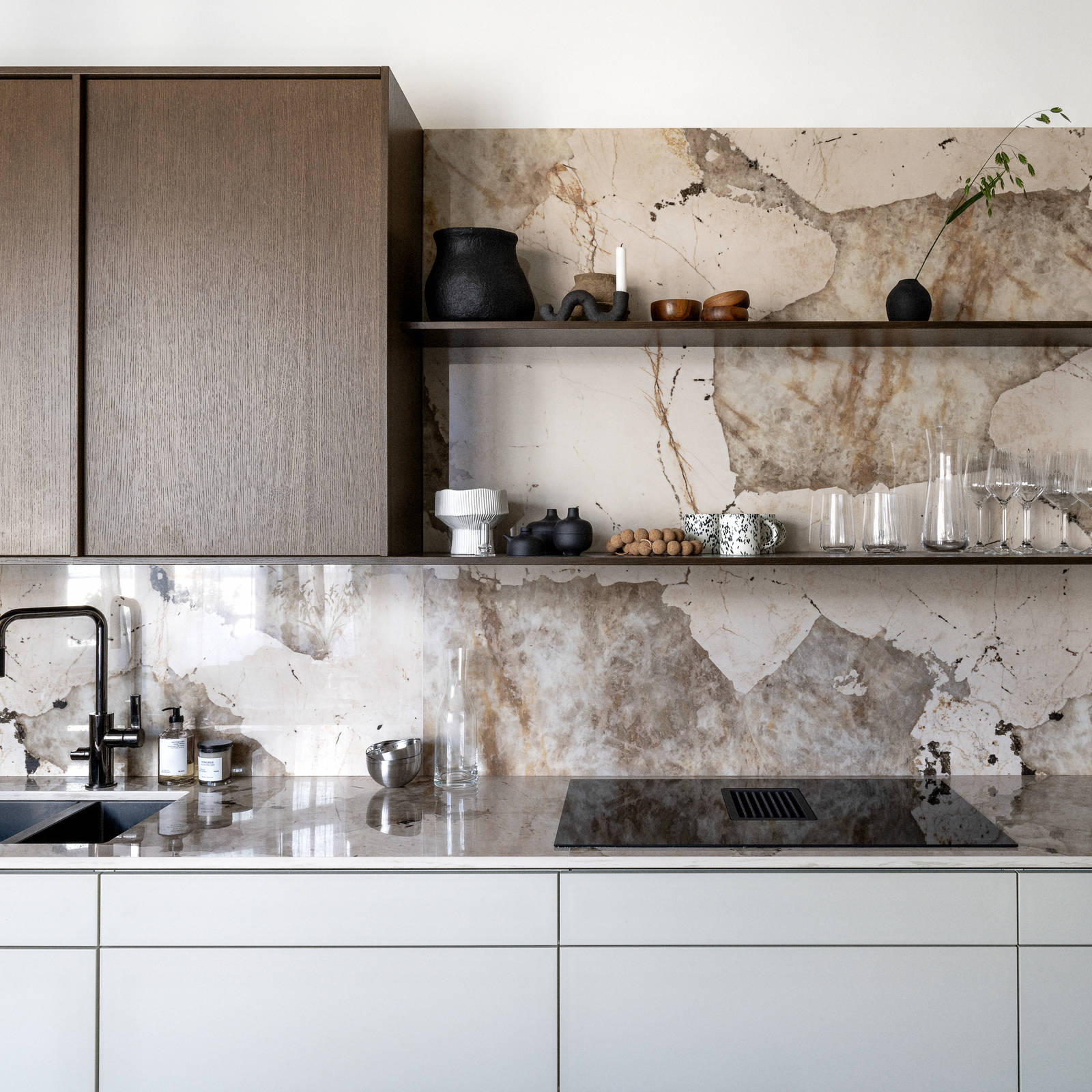 Køkken med en kombination af køkkenbord i beige Arkitekt Plus Sand med overskabe i Signatur Ekbacken fineret egetræslåge i brunbejdset fra Marbodal, bordplade og stænk, der matcher, og åbne væghylder i brunbejdset eg finer.